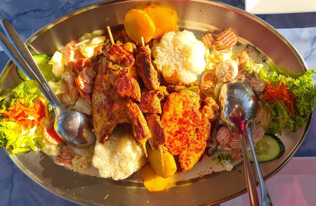 Grillplatte mit Fleischspezialitäten und Beilagen im Helios